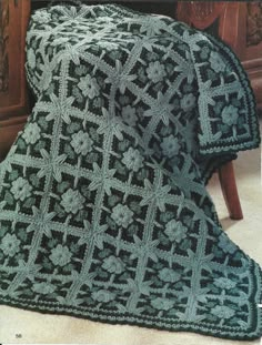 a green crocheted blanket sitting on top of a wooden table next to a chair