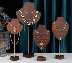 four wooden jewelry stands with necklaces on them