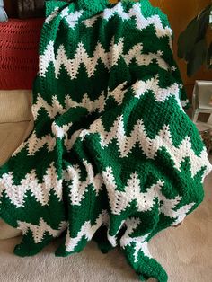 a green and white crocheted blanket sitting on top of a couch