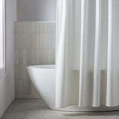 a white bathtub sitting next to a window in a bathroom under a shower curtain