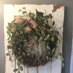 a wreath is hanging on the wall with ivy and burlock tied around it