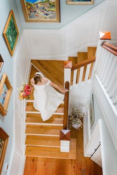 a woman in a white dress is walking down the stairs with flowers on her bouquet