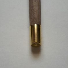 a close up of a wooden object on a white surface with a gold colored handle