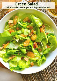 green salad with mandarin oranges and sugared almonds in a white bowl on a woven place mat