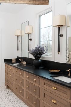 a bathroom with two sinks, mirrors and lights on the wall above them is shown