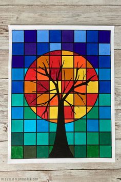 a stained glass window with a tree in the center and colorful squares around it on a wooden surface