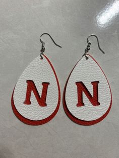 two pairs of earrings with the letter n in red and white painted on each earring