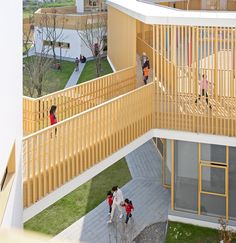 several children are walking up and down the stairs in an open area with wooden balconies