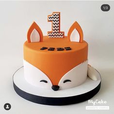 a cake decorated with an orange and white fox head, the number one on top