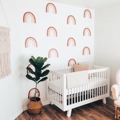 a baby's room with a white crib and rainbow wallpaper on the walls