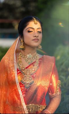 a woman in an orange and gold sari with her hands on her hips, looking off to the side