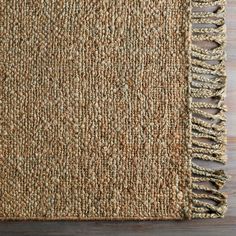 a brown rug with fringes on top of wooden flooring next to a wall