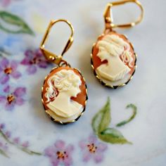 Glorious handmade Victorian small carnelian cameo earrings set in gold brass scallop bezels and gold plated brass shield lever back ear wires.  These gold cameo earrings are handmade with silhouette cameos in ivory hues on carnelian background. The cameos are made of quality acrylic resin.   All hand set by me - Ms. B.  Thoughtful birthday gift for her. . . . ꕥ  Earrings Length :  approx.  1 1/4" inches long ꕥ  Cameo : Acrylic Resin, Oval 18x13mm ꕥ  Bezel Settings : 1/2" wide by 3/4" long ↝   Se Victorian Cameo, Cameo Pendant Necklace, Victorian Earrings, Artisan Jewelry Handmade, Cameo Earrings, Cameo Jewelry, Cameo Necklace, Cameo Pendant, Birthday Gift For Her