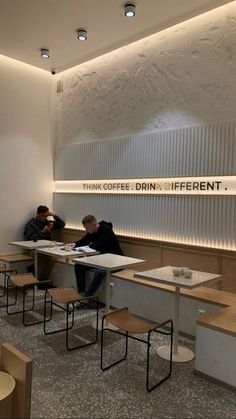 two men sitting at tables in a coffee shop with their backs turned to the side