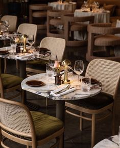 the table is set with wine glasses, plates and napkins on it for dinner