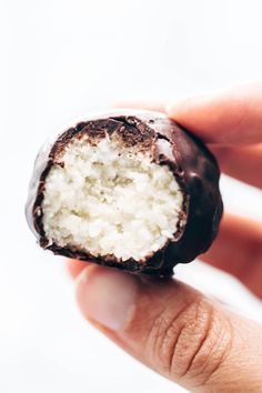 a hand holding a half eaten chocolate covered donut with white frosting on top