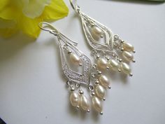 Freshwater Pearls are hung on fabulous handcrafted drops of Fine Silver. Lovely bridal earrings. Just right for that special holiday dress or even your favorite jeans when you need a little pick me up. These show stoppers will be noticed! Pearls are the birthstone for June and for the 30th year of marriage. The inner glow (orient) of pearls is thought to tap inner-wisdom and nurture love. Pearls are also believed to signify innocence and faith. Pearls are soft and should be treated delicately. N Dangling Beads Bridal Earrings For Wedding, White Pierced Chandelier Earrings For Anniversary, Handmade Teardrop Bridal Earrings For Wedding, Wedding Silver Earrings With Dangling Beads, Sterling Silver Dangling Beads Earrings For Wedding, Wedding Bridal Earrings With Dangling Beads, Wedding Bridal Dangle Earrings With Beads, Delicate Dangling Beads Earrings For Wedding, Wedding Pearl Drop Earrings With Dangling Beads