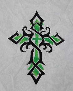 an ornate cross with green and black designs on white paper, as well as the word faith