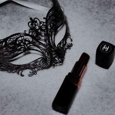 a black mask and lipstick are laying on the floor