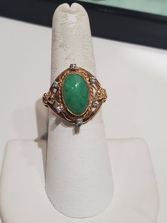 You are viewing a beautiful 14k solid gold green jade and diamond ring. The ring size : 6 3/4 The total gram weight of the ring is : 5.61 grams. The ring marked 14k inside and tested 14k. Its a very well made ring. The jade ring surround with 6 round dia total of .12 ctw. The jade stone measures 13mm x 8mm oval shape . Please take a closer look at the video and photos. If you have a question send me a message. Collectible Green 14k Stamped Jewelry, Elegant 14k Stamped Emerald Ring, Green Rings With Diamond Accents For Formal Occasions, Formal Green Rings With Diamond Accents, Heirloom Jade Jewelry In Green, Heirloom Green Jade Jewelry, Art Deco Green Emerald Ring In 14k Gold, Art Deco Emerald Ring In 14k Gold, Green Diamond Art Deco Rings