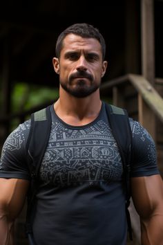 a man with a beard wearing a black t - shirt is standing in front of stairs