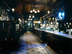 a dimly lit bar with lots of bottles on the shelves and lights hanging from the ceiling