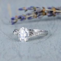 a close up of a ring on a table with lavenders and flowers in the background