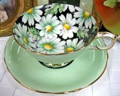 a tea cup and saucer decorated with daisies