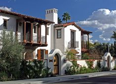 a white house with brown shutters and balconies on the roof is shown