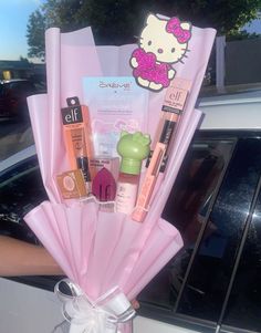 a hello kitty themed bouquet in a pink plastic vase with lip glosses and mascara