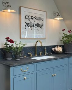 a kitchen with blue cabinets and gold faucets on the countertop, potted plants in pots