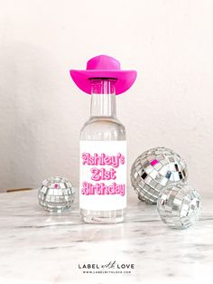 a pink hat is on top of a bottle with disco balls around it and the label says 21st birthday