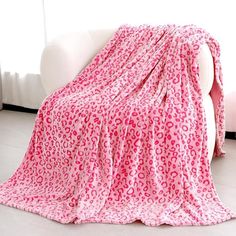 a pink leopard print blanket sitting on top of a white couch