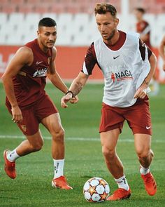 two men playing soccer on a field with one holding the ball while the other is running