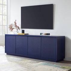 an entertainment center with a flat screen tv mounted on it's sideboard in a living room