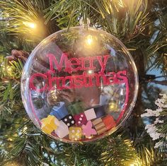 a christmas ornament hanging from a tree filled with toys and letters that read merry christmas