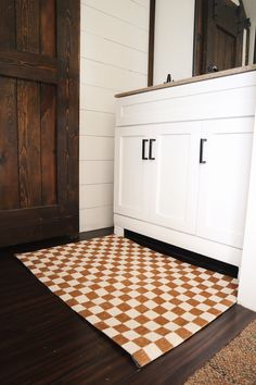 a brown and white checkered rug sitting on top of a floor next to a wooden door