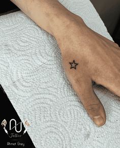 a person's hand with a small star tattoo on it