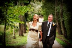 a man and woman walking down a path holding hands