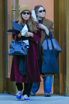 two women walking down the street carrying bags