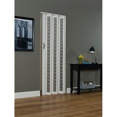 an empty room with a table and two white closets on the wall next to a wooden floor