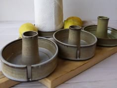 four bowls and two rolls of toilet paper on a wooden tray with lemons in the background