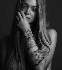 a woman with long hair and tattoos on her arm