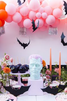 a table topped with cake and candles next to balloons in the shape of dracula's head