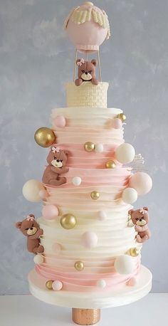 a three tiered cake with teddy bears on top and pink icing, gold accents