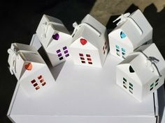 several small white houses sitting on top of a table next to each other with hearts painted on them