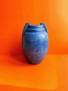 a blue vase sitting on an orange surface