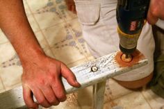 a man using a drill to fix a tile floor with a hammer and naildriver