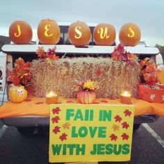 a table with pumpkins, hay bales and candles in front of a truck