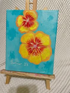 an easel with a painting on it that has two flowers painted on the side